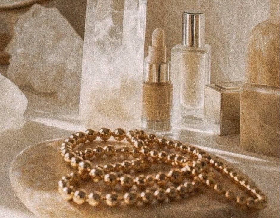 Decorative setting with crystals, mirror, and jewelry on a surface.